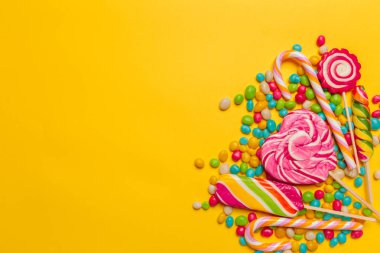 sarı arka plan üzerinde renkli şekerler, üstten görünüm