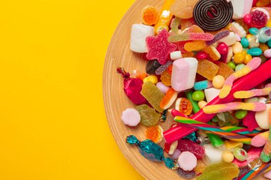 sarı arka plan üzerinde renkli şekerler, üstten görünüm