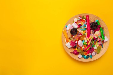 sarı arka plan üzerinde renkli şekerler, üstten görünüm