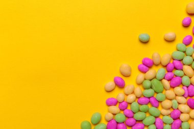 sarı arka plan üzerinde renkli şekerler, üstten görünüm
