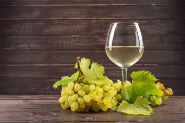 şarap cam ve ahşap masa üzerinde üzüm salkımı