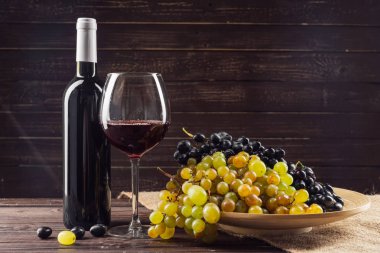 Şarap şişesi, cam ve ahşap masa üzerinde üzüm yakın çekim
