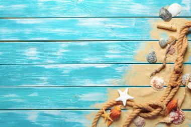 deniz mavi ahşap arka plan üzerinde kum üzerinde deniz kabukları ile deniz ip. Üstten görünüm