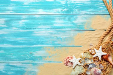 denizin mavi ahşap arka plan üzerinde kum üzerinde birçok farklı deniz kabukları ile deniz ip. Üstten görünüm