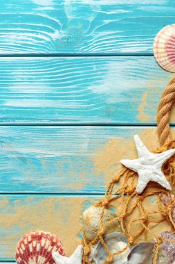 deniz mavi ahşap arka plan üzerinde kum üzerinde deniz kabukları ile deniz ip. Üstten görünüm