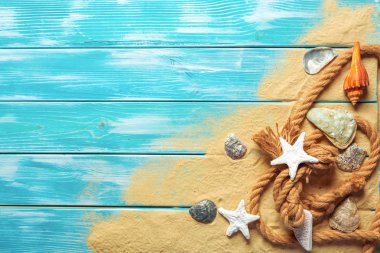 deniz mavi ahşap arka plan üzerinde kum üzerinde deniz kabukları ile deniz ip. Üstten görünüm