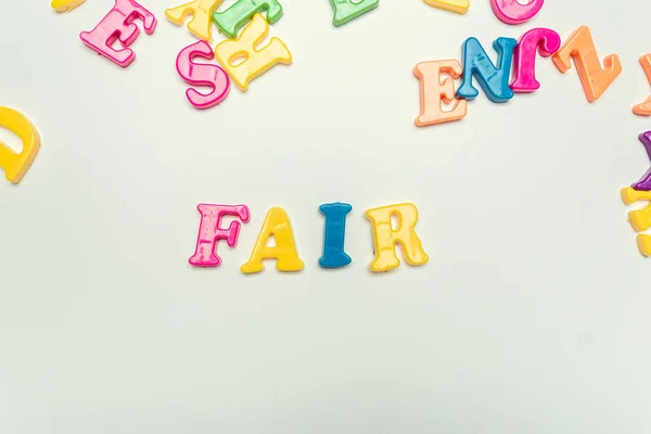 Plastic colorful letters with the text: Fair close up on white background