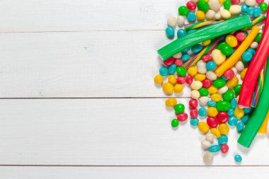 Ahşap arka plan üzerinde renkli çeşitli şekerler