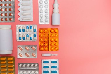 Pembe arka planda ilaç hapları. Üst görünüm