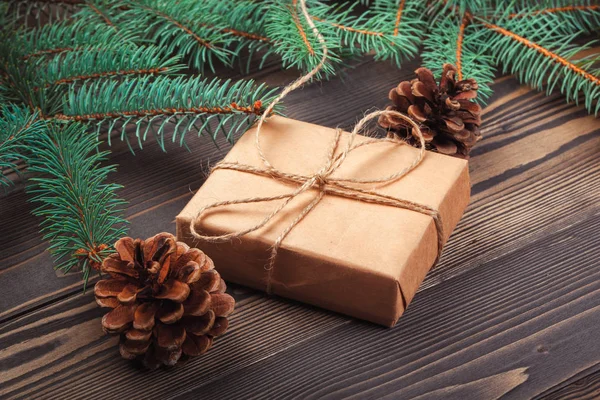 Ahşap masa üzerinde Noel hediye kutusu ve köknar ağacı dalları.