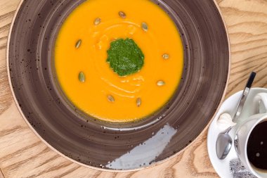 Kırsal ahşap arka planda bir kase balkabağı çorbası.