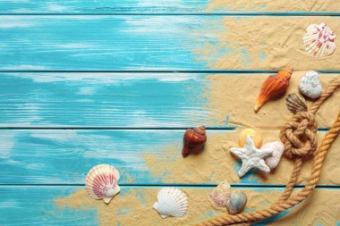 Deniz kabukları ve kum mavi ahşap zemin üzerine