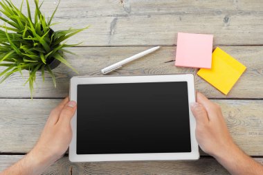 tablet cihaz ahşap çalışma masa üzerinde tutan bir adam elinde