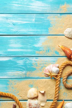 Deniz kabukları ve kum mavi ahşap zemin üzerine
