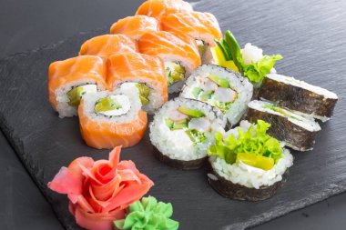 Siyah arduvaz plaka üzerinde lezzetli suşi rulo.