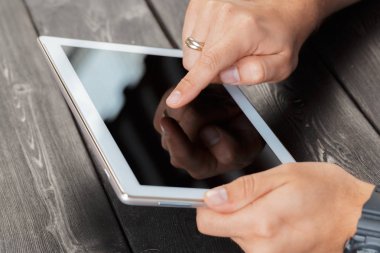 tablet cihaz ahşap çalışma masa üzerinde tutan bir adam elinde