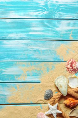 Deniz kabukları ve kum mavi ahşap zemin üzerine