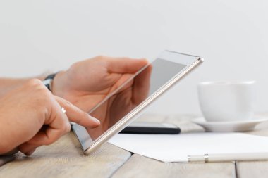 tablet cihaz ahşap çalışma masa üzerinde tutan bir adam elinde