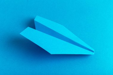 Düz bir kağıt uçak pastel mavi renk arka plan üzerinde yatıyordu