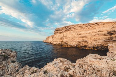Plajda kayalıklarla arka plan mavi bir deniz üzerinde açık gökyüzü
