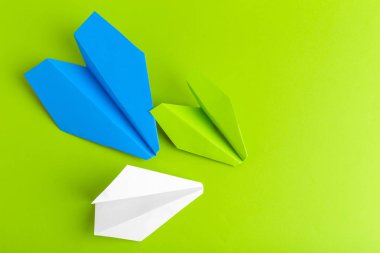 Düz bir kağıt uçak yeşil pastel renk arka plan üzerinde yatıyordu