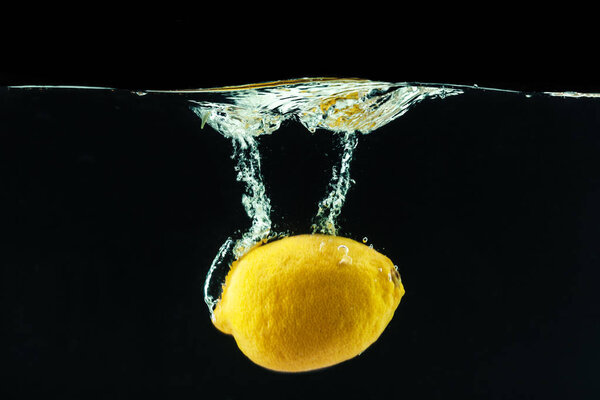 fresh yellow lemon in water splash on black background