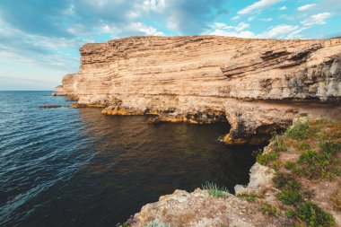 Plajda kayalıklarla arka plan mavi bir deniz üzerinde açık gökyüzü