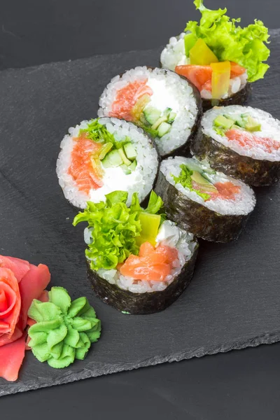 Japanese restaurant, sushi roll on black slate plate.