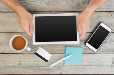 tablet cihaz ahşap çalışma masa üzerinde tutan bir adam elinde