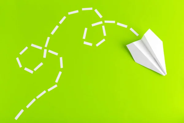 Paper airplane connected with dotted lines on green background. Business concept