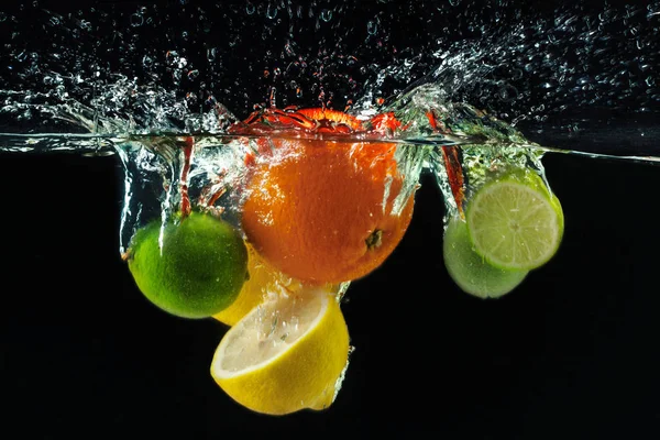 Muitos Frutos Salpicando Água Contra Fundo Preto — Fotografia de Stock