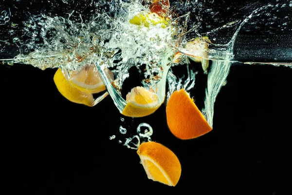 Muitos Frutos Salpicando Água Contra Fundo Preto — Fotografia de Stock