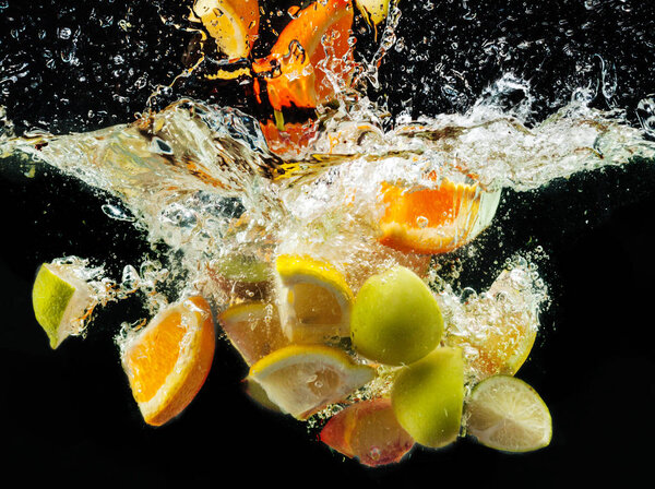 много фруктов, плескающихся в воду на черном фоне
 