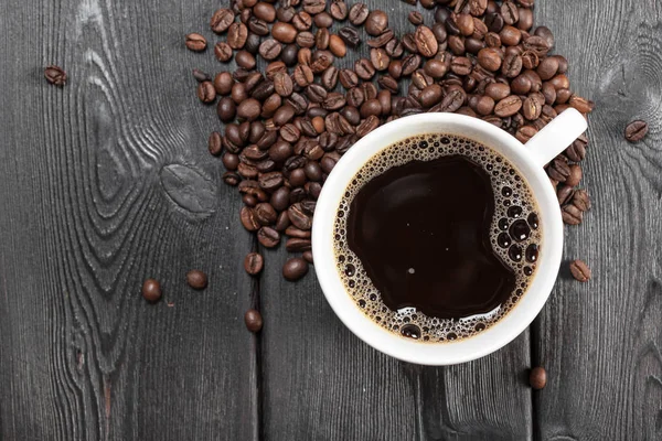 木製の背景にコーヒーと豆のカップ — ストック写真