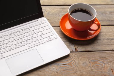 Tahta masadaki turuncu tabakta bir fincan kahve. Ofis içi