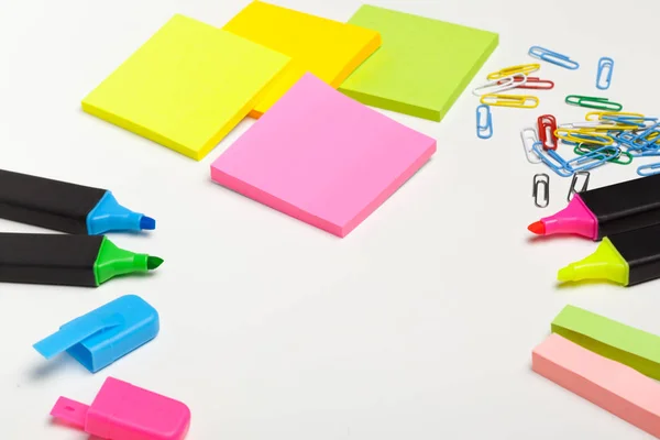 Sticky notes with markers, colored pens, paper clips laying on a table