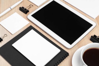 Masaüstünde not defteri, malzeme ve kahve fincanı olan dijital tablet. 