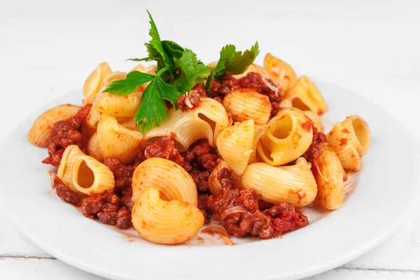 Pasta with meat, tomato sauce and vegetables on the table