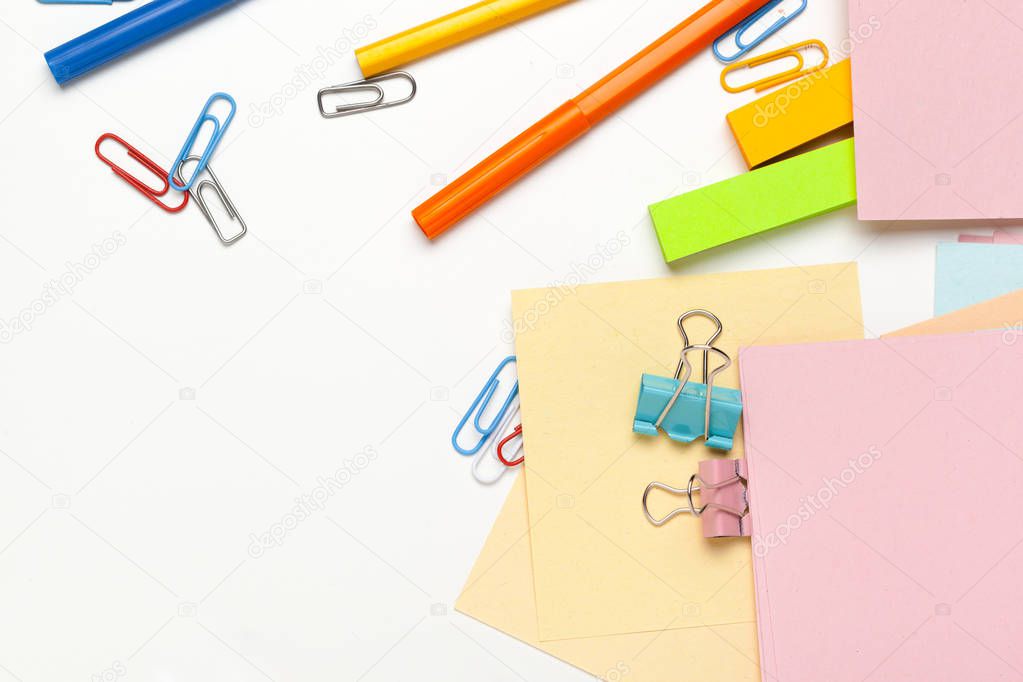 Sticky notes with markers, colored pens, paper clips laying on a table