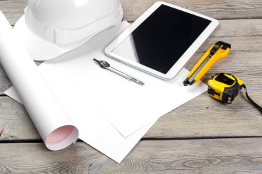 Mimari işyerinin plan kağıdıyla üst görünümü ve boş ekranlı dijital tablet