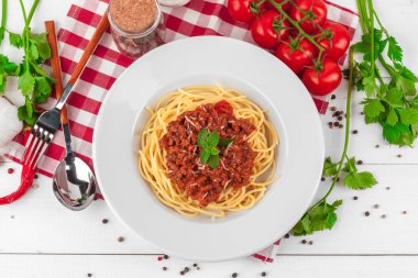 Etli makarna, domates sosu ve sebzeler masada.