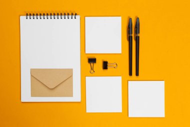 Model konsepti. Sarı arka planda kağıtlar. Üst görünüm, düz görünüm, kopyalama alanı