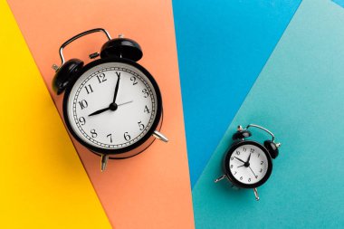 Renk bloğu arka planında klasik siyah alarm saati