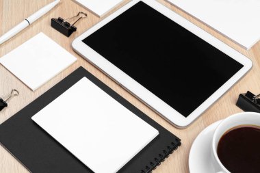Masaüstünde not defteri, malzeme ve kahve fincanı olan dijital tablet. 
