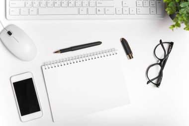 Bilgisayar klavyesi ve malzemeleri olan modern beyaz ofis masası. Kopyalama alanı olan üst görünüm, düz yatay.