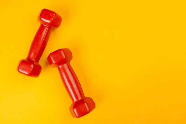 Fitness dumbbells on bright yellow background. Fitness concept