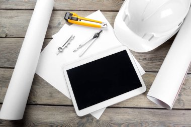 Mimari işyerinin plan kağıdıyla üst görünümü ve boş ekranlı dijital tablet