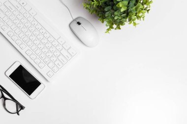 Bilgisayar klavyesi ve malzemeleri olan modern beyaz ofis masası. Kopyalama alanı olan üst görünüm, düz yatay.