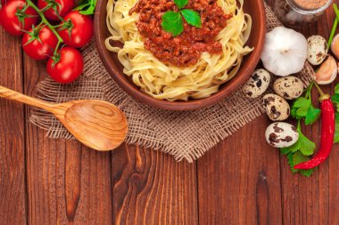 Etli makarna, domates sosu ve sebzeler masada.