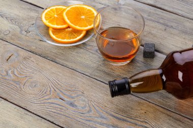 Koyu ahşap arka planda portakal meyveli viski bardağı.